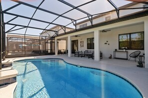 A swimming pool with a glass ceiling, surrounded by outdoor furniture and a patio area. - 6BR Themed Villa Private Pool Near Universal (Orlando)