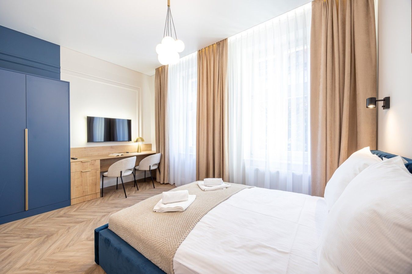 A hotel room with a bed, a desk, a chair, and a wardrobe.
