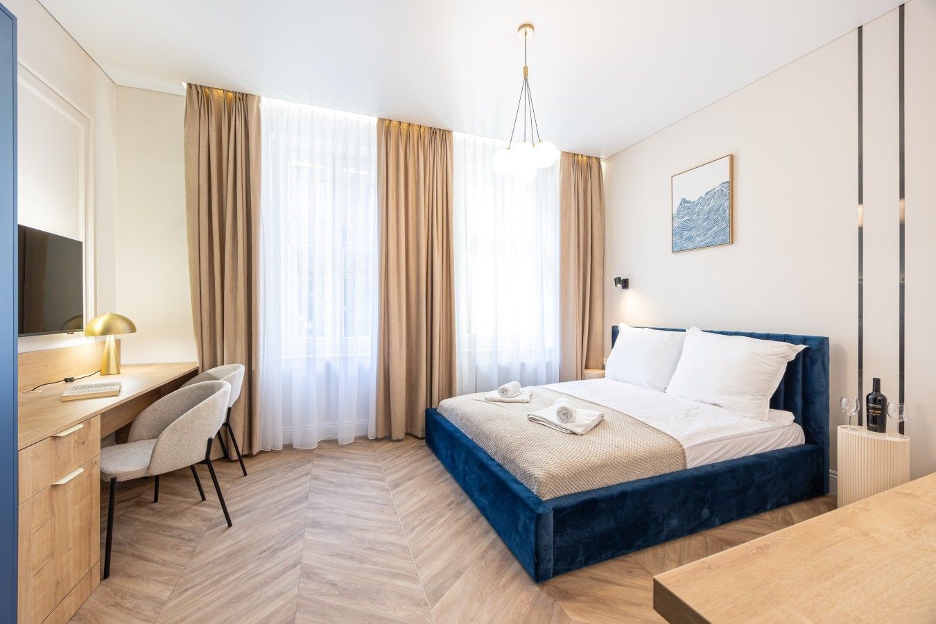A hotel room with a bed, desk, chair, and a large window with curtains.