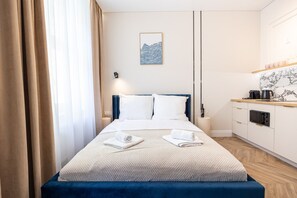 A hotel room with a bed, a bedside table, a small kitchen area, and a window with curtains. - Armas 5 Granatowa Elegancja z Klimatyzacj (Bydgoszcz)