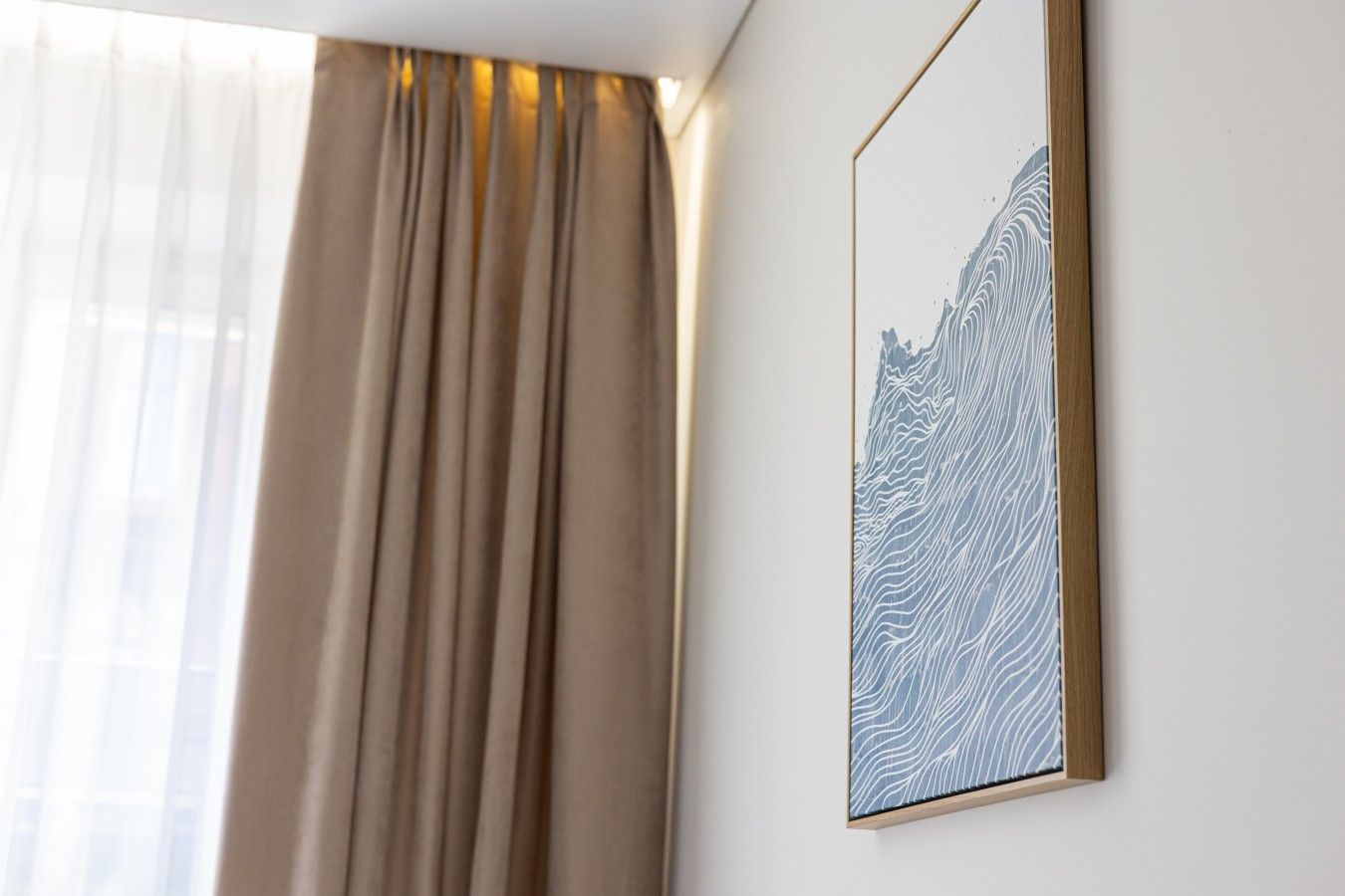 A room with a window, a curtain, and a framed artwork on the wall.