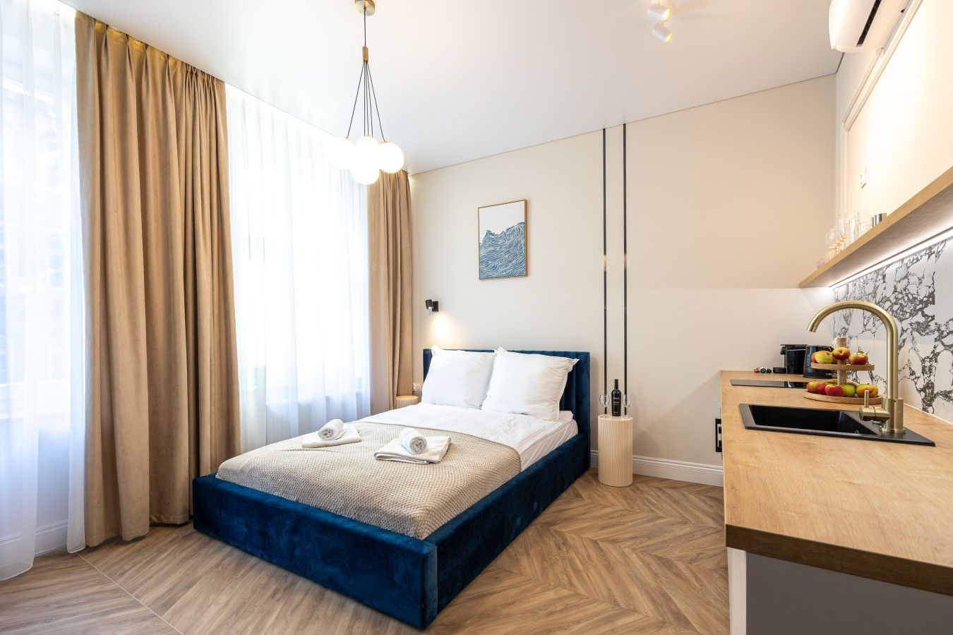 A hotel room with a bed, a desk, a sink, and a window with curtains.