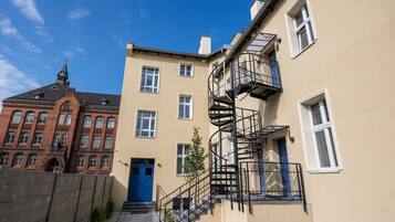 A building with a blue door, a spiral staircase, and a red brick structure in the background.