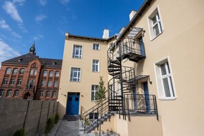 A building with a blue door, a spiral staircase, and a red brick structure in the background. - Armas 5 Granatowa Elegancja z Klimatyzacj (Bydgoszcz)