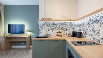 A modern kitchen with a built-in stove, a sink, and a countertop with a fruit display.