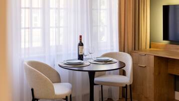 A dining area with a round table, two chairs, a bottle of wine, and a glass.