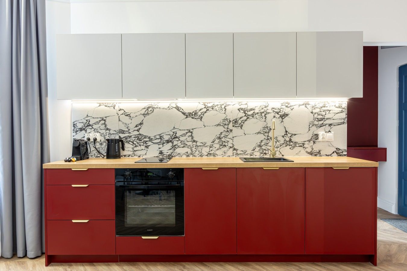 Een moderne keuken met een marmeren spatwand, een inbouwoven en een spoelbak.