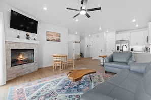 A modern living room with a fireplace, a grey sofa, a wooden coffee table, and a patterned rug. - Bw1204-1 (Keystone)