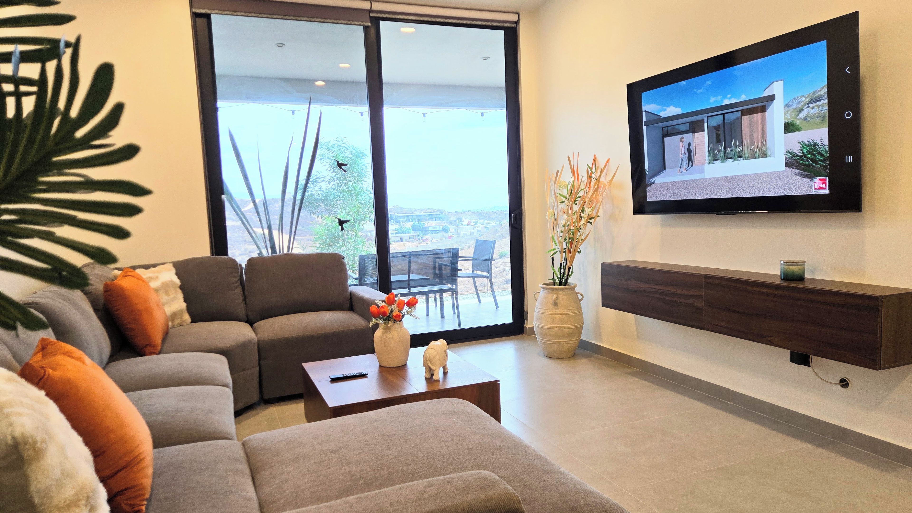 A modern living room with a sofa, coffee table, and a flat-screen TV mounted on the wall.