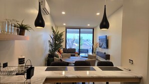 A modern dining area with a marble table, black chairs, and pendant lighting. - Brand New, A/C, Starlink, Terrace, 5 auto Pkg private, & Pet friendly (Ensenada)