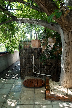 Une fontaine en pierre avec un banc en bois et un tuyau d’arrosage.