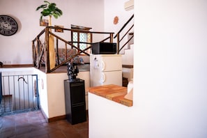 Une cuisine avec un escalier en bois, une machine à café et un four à micro-ondes posés sur un meuble blanc.