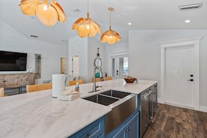 A modern kitchen with a central island, stainless steel appliances, and pendant lighting. - Beach Bliss -waterfront Pool Spa -dock Golf Cart Boat Lift (Anna Maria)