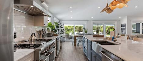 Cocina moderna con electrodomésticos de acero inoxidable, una isla grande e iluminación colgante.