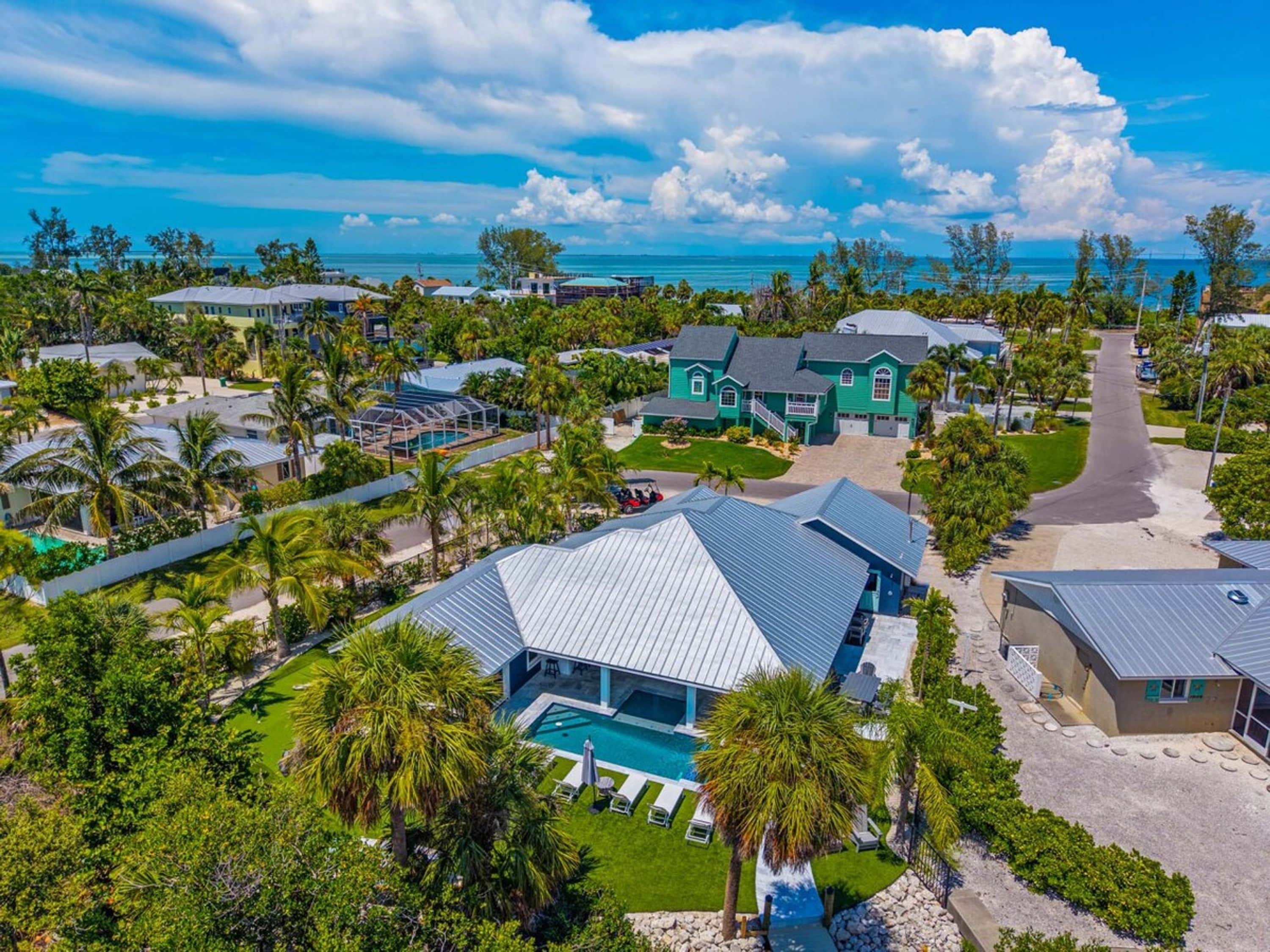 A residential area with multiple houses, a swimming pool, and a clear view of the ocean.