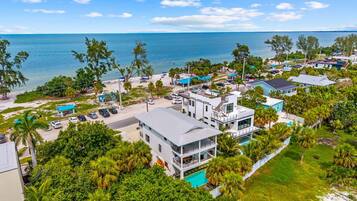A modern beachfront property with a pool, multiple buildings, and a view of the ocean.