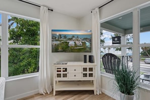 A room with a large window, a white cabinet with drawers, a mounted painting of a coastal scene, and a sign reading 'Wander'. - Waves - Heated Pool -steps to Beach -golf Cart - Putting Green (Anna Maria)
