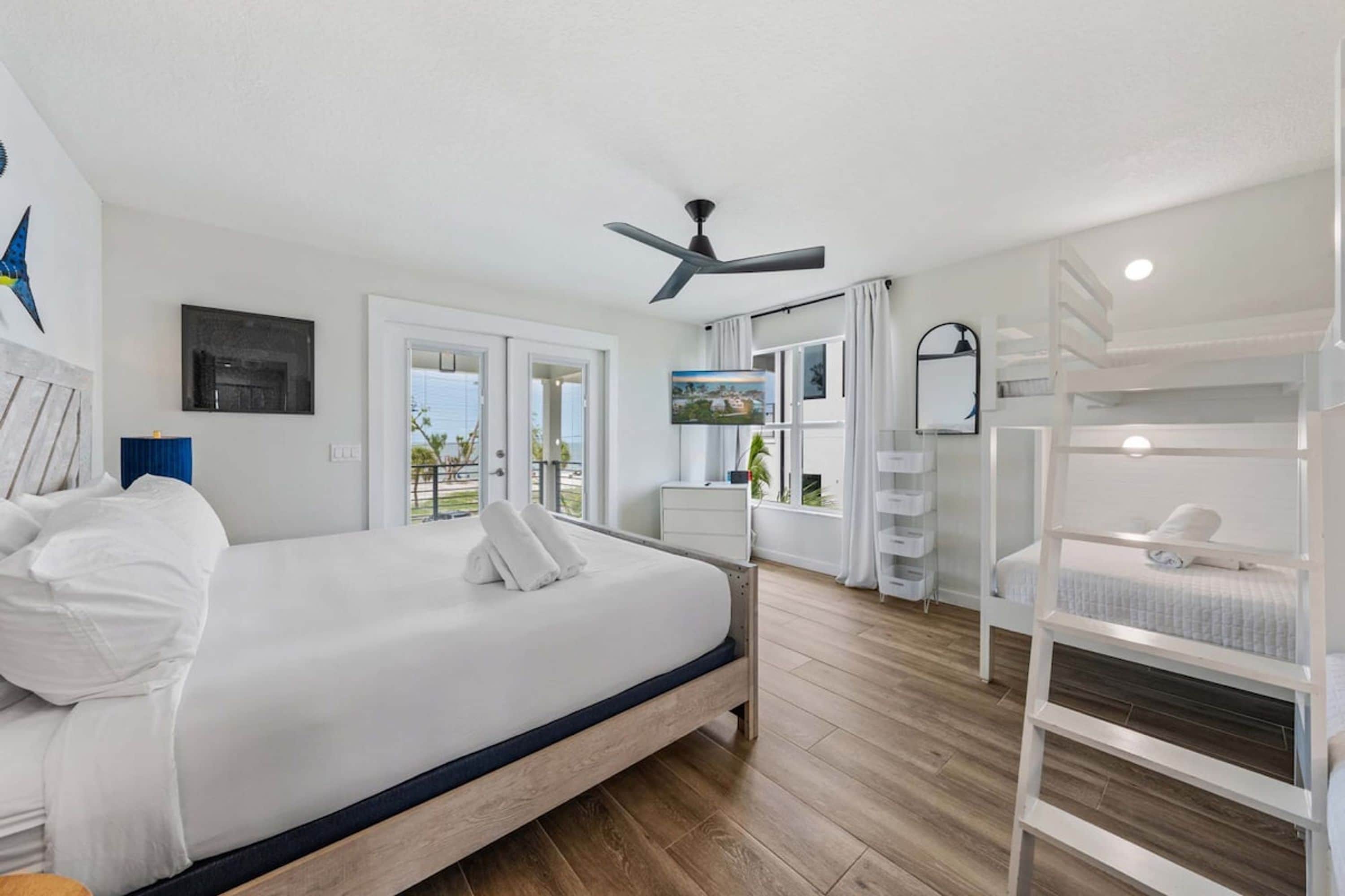 A hotel room with a large bed, a ceiling fan, a window with curtains, and a view of the outdoors.