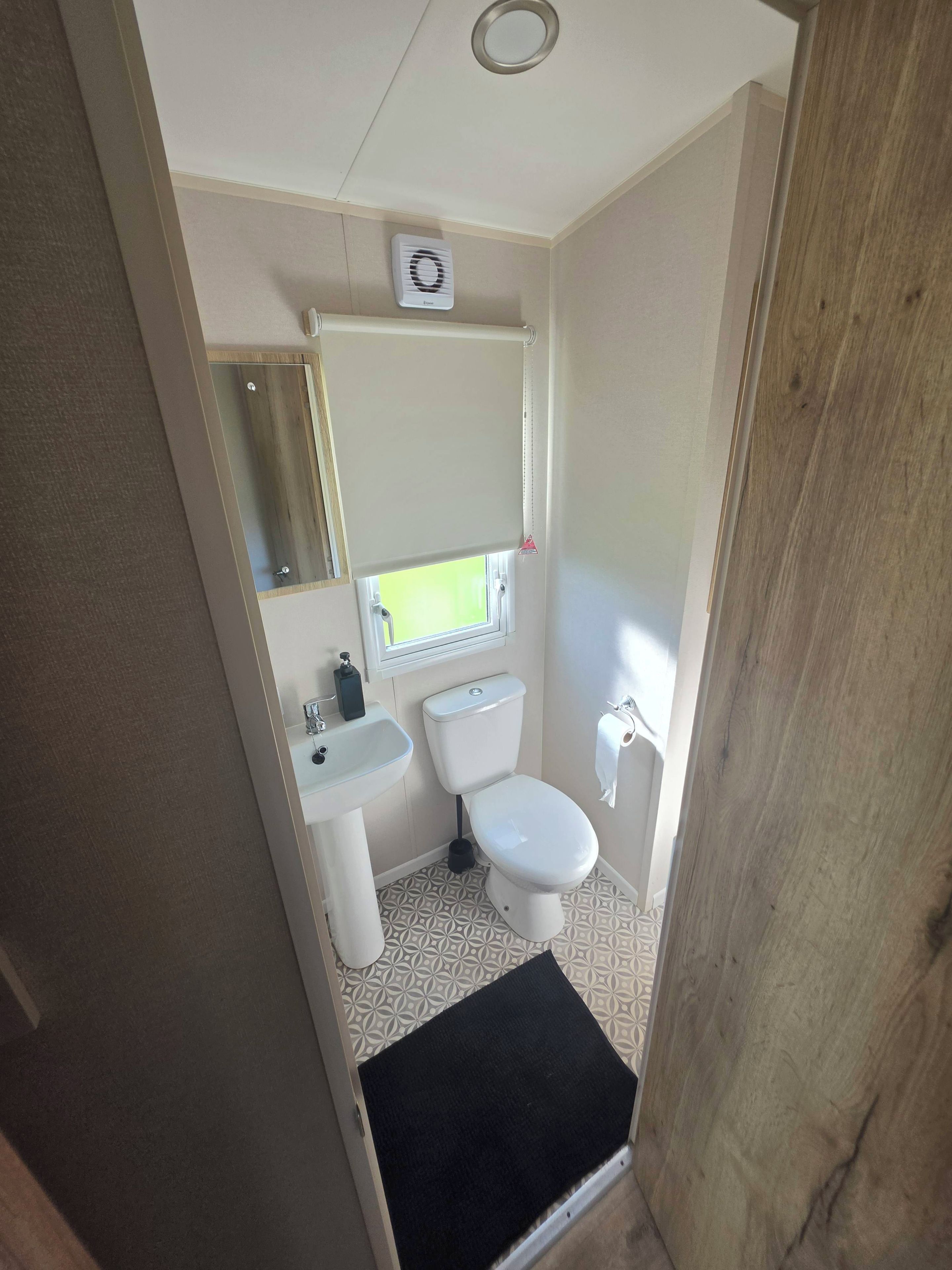 A compact bathroom with a toilet, sink, and mirror.