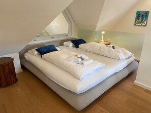 Ein Schlafzimmer mit zwei Betten, einem Fenster, einem Nachttisch und einem Wandbild.