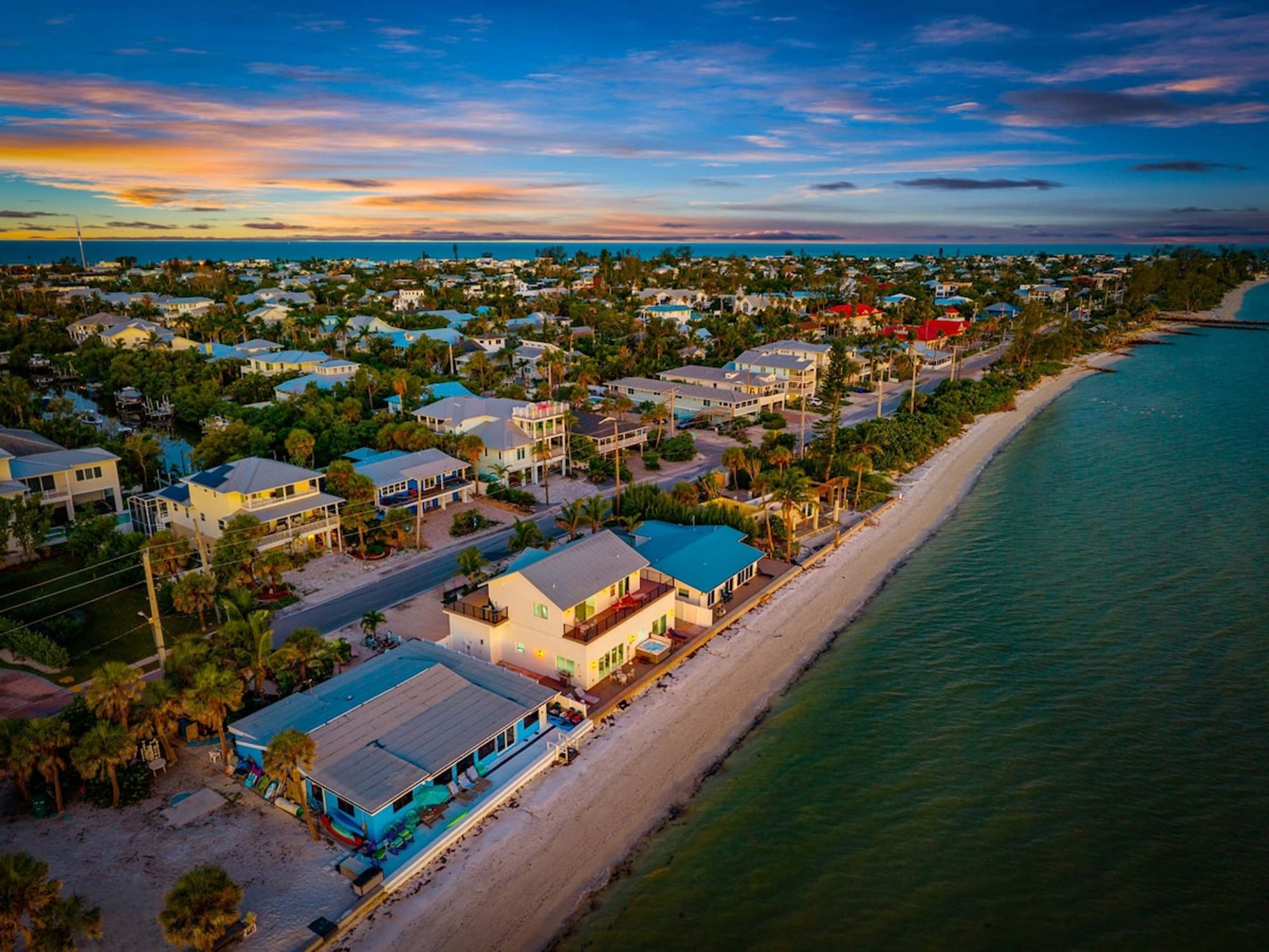 A coastal residential area with houses along the beachfront, featuring a mix of single and multi-story buildings.