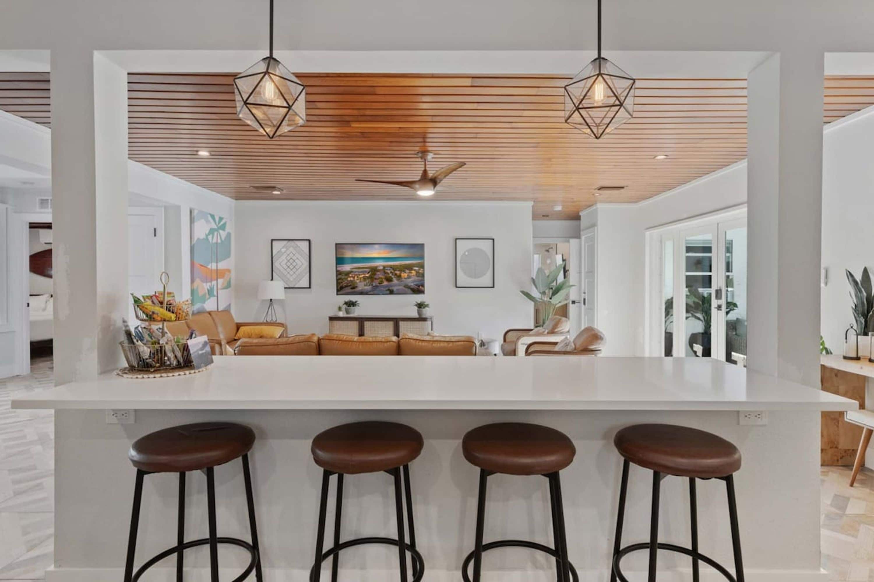 A modern kitchen with a central island, bar stools, and pendant lighting.