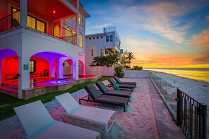 A beachfront property with a pool area, lounge chairs, and a view of the ocean at sunset. - Serendipity Deux -luxury Beachfront Pool Spa - Golf Cart -elevator (Anna Maria)