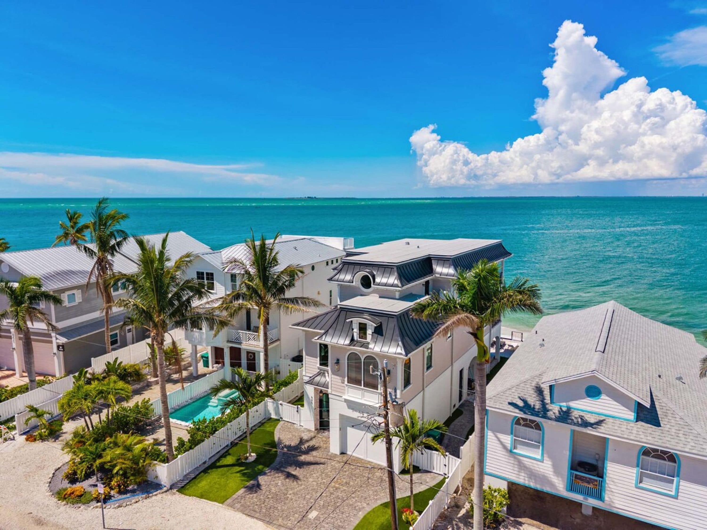 A coastal property with multiple buildings, a swimming pool, and palm trees.