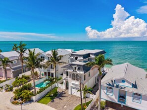A coastal property with multiple buildings, a swimming pool, and palm trees. - Serendipity Deux -luxury Beachfront Pool Spa - Golf Cart -elevator (Anna Maria)