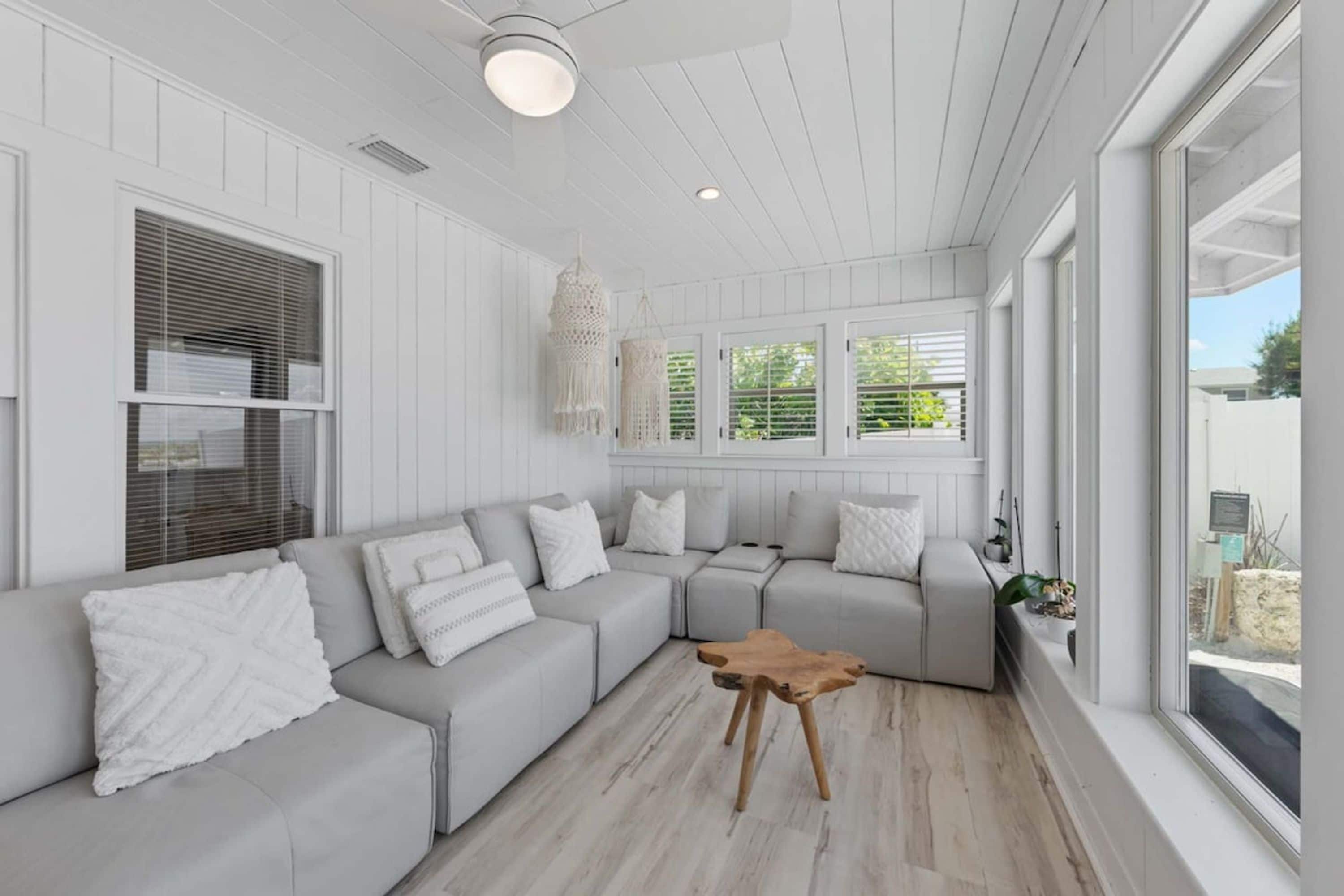 A modern living room with a sectional sofa, a wooden coffee table, and a view of the outdoors.