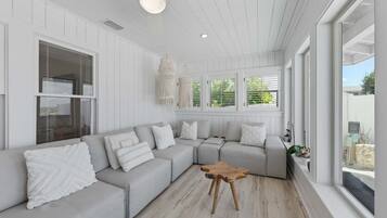 A modern living room with a sectional sofa, a wooden coffee table, and a view of the outdoors.