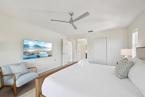 Habitación de hotel con cama, una silla, ventilador de techo, un cuadro y vista a un paisaje.