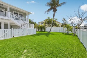 A residential property with a well-maintained lawn, a white picket fence, and a two-story house with a balcony. - Salt Sol - Heated Pool -canal-front -golf Cart -dock (Anna Maria)