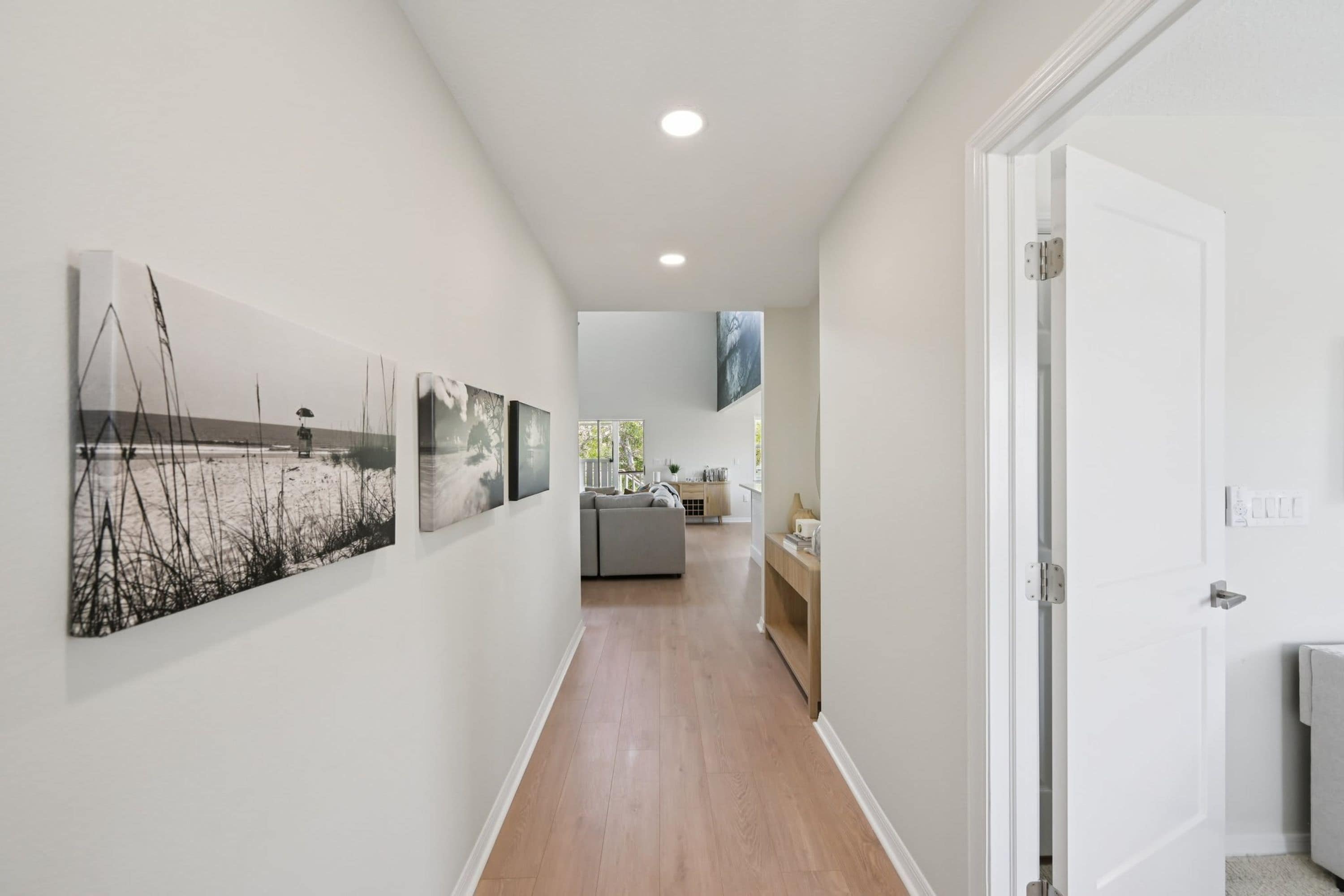 A hallway with wooden flooring, white walls, and a door on the right.