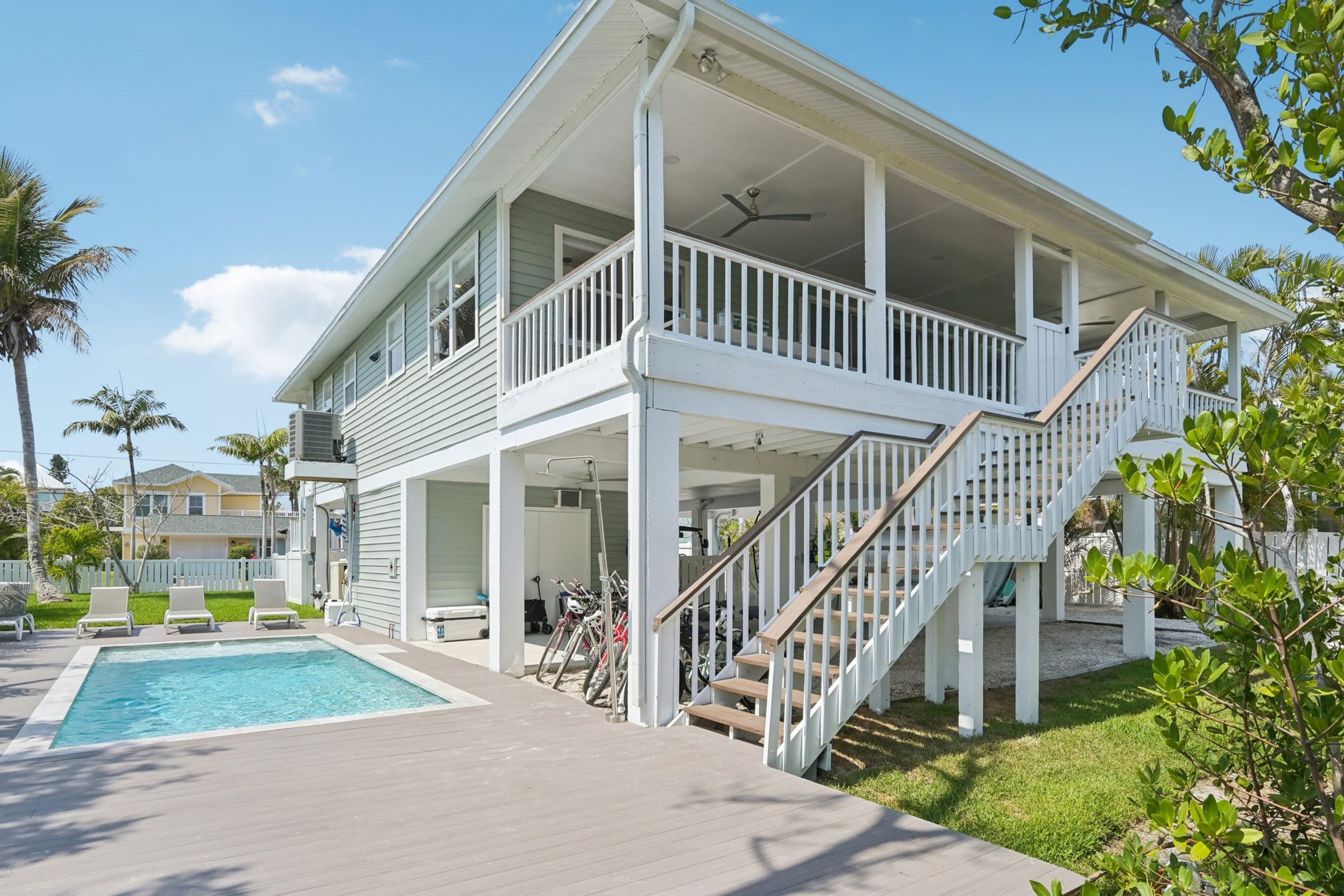 A two-story building with a covered outdoor area, a pool, and a staircase.