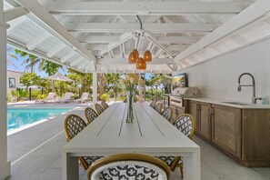 A covered outdoor dining area with a pool, a grill, and a view of the poolside. - Limefish Luxury - Gulf Front Pool -sunset Views -beach Access (Holmes Beach)