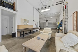 A spacious room with a large table, a sofa, and a chair. There are storage shelves and a door leading to another room. - Serendipity -beachfront -hot Tub -golf Cart -elevator (Anna Maria)