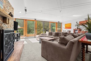 A modern living room with a large sofa, a coffee table, and a fireplace. There is a large window providing a view of the outdoors. - D1781-4 (Keystone)