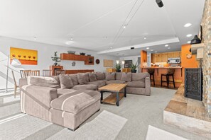 A modern living room with a sectional sofa, a coffee table, and a dining area with a kitchen in the background. - D1781-4 (Keystone)