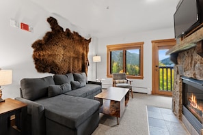 A modern living room with a grey sofa, a coffee table, a fireplace, and a large fur rug. - Rh2284-1 (Keystone)