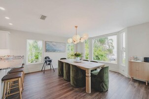 A spacious kitchen with a dining area, large windows, and a view of greenery.