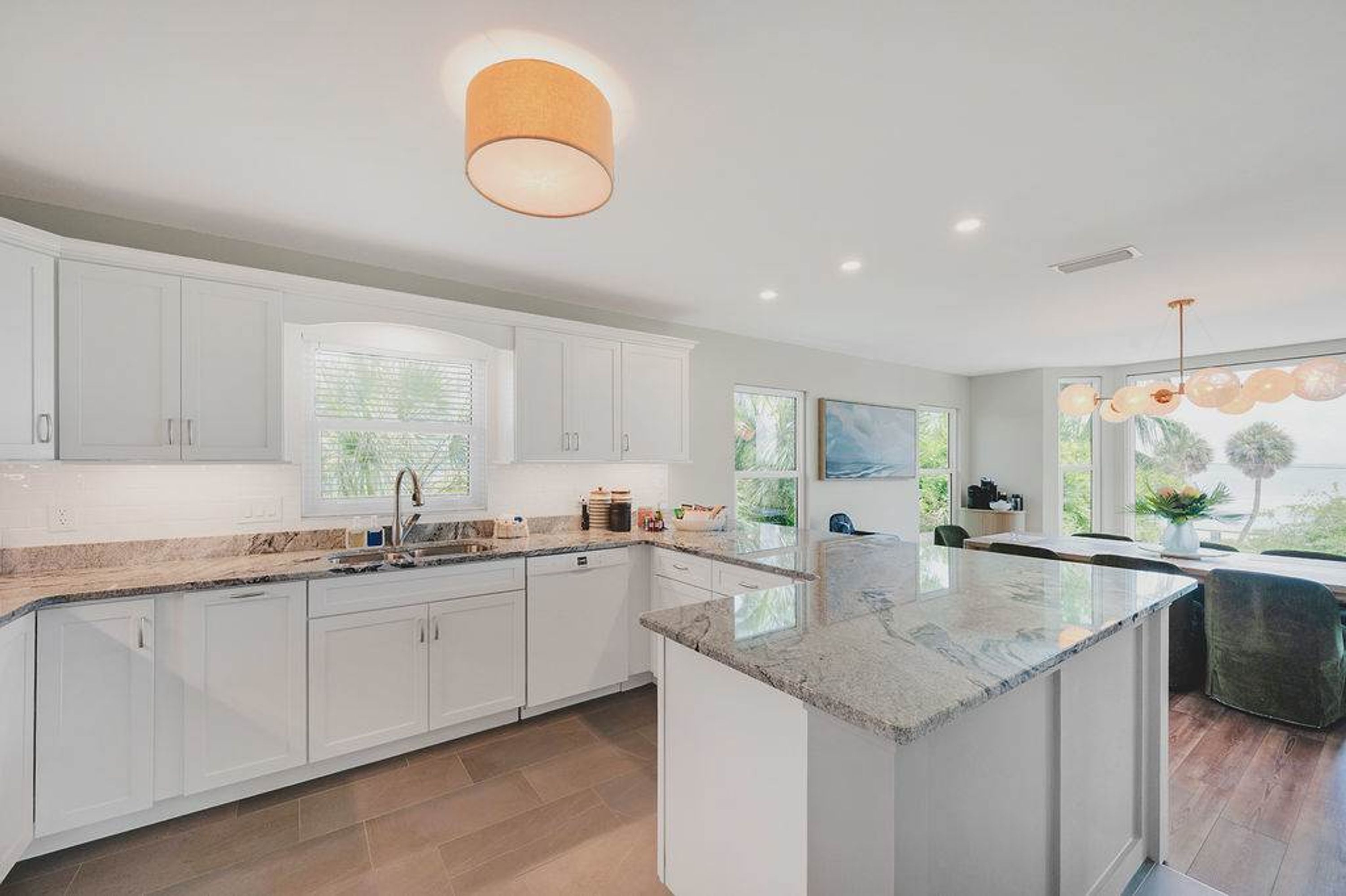 A modern kitchen with white cabinetry, a large island, and a pendant light.