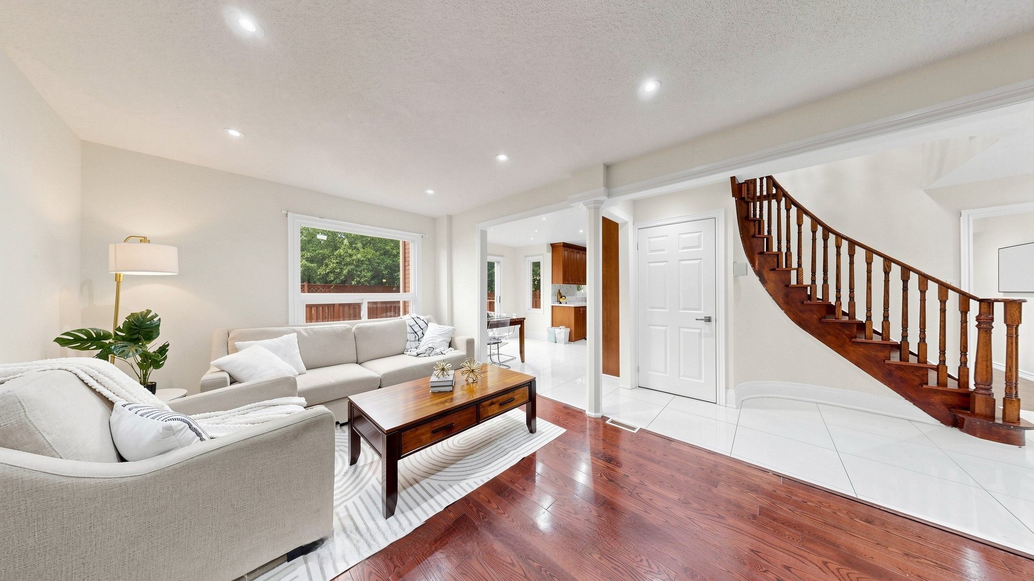 A spacious living room with a sofa, coffee table, and a staircase leading to a kitchen.