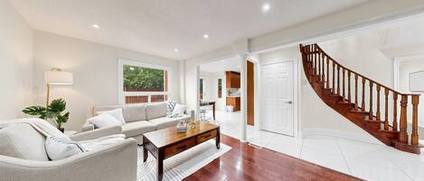 A spacious living room with a sofa, coffee table, and a staircase leading to a kitchen.