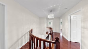 A hallway with a wooden staircase, white walls, and a ceiling light fixture. - Brampton Gem - Spacious 4BR & Parking (Brampton)