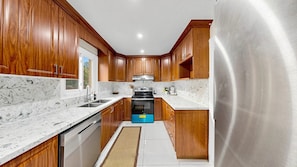 A kitchen with wooden cabinets, a stainless steel refrigerator, a dishwasher, and a stove. - Brampton Gem - Spacious 4BR & Parking (Brampton)