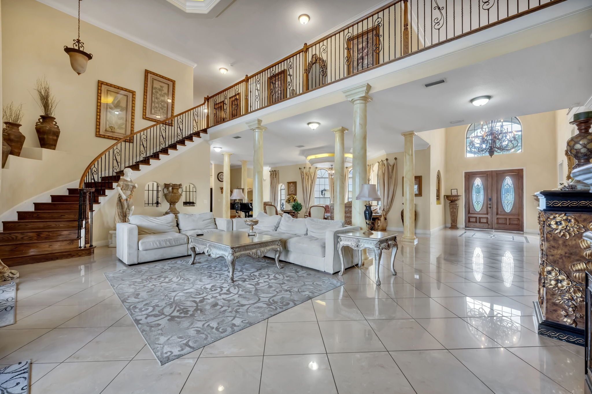 A spacious living area with a grand staircase, elegant furniture, and decorative elements.