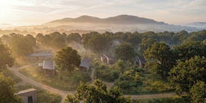 A rural landscape with several traditional-style buildings surrounded by dense greenery and hills in the background. - Arbora 2.0 Spa (Malvern)