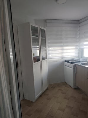 A kitchen with white cabinets, a dishwasher, and a window with blinds. - New Listing (Rota)