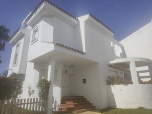 A white two-story building with a flat roof, a front porch, and a staircase leading to the entrance. - New Listing (Rota)